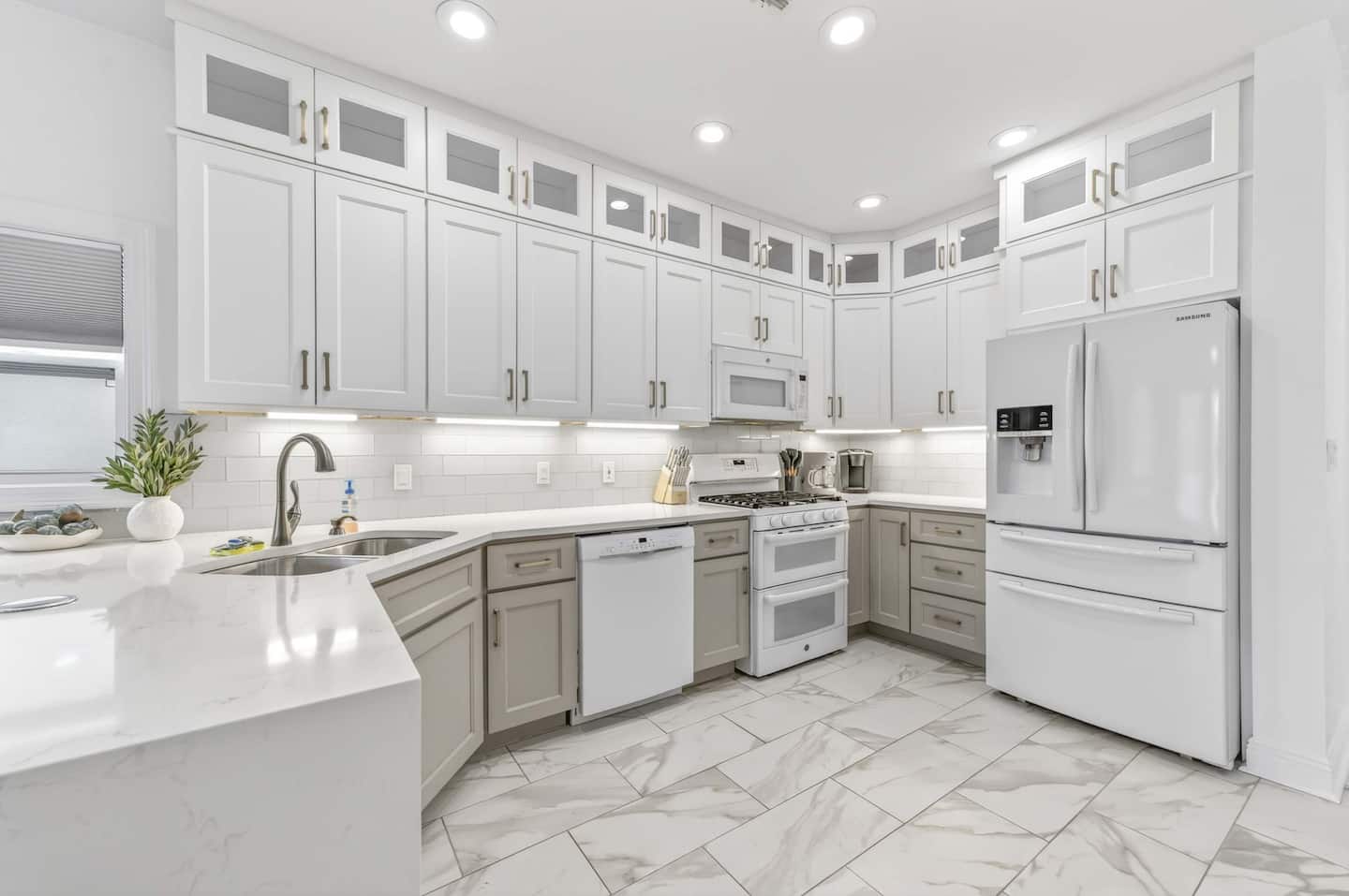 Modern kitchen featuring white cabinetry, stainless steel appliances, and marble flooring, designed for guest comfort.