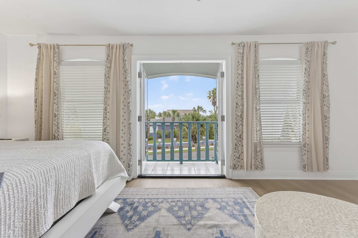 Bright bedroom with a balcony view, featuring light curtains and a cozy atmosphere, ideal for relaxation.
