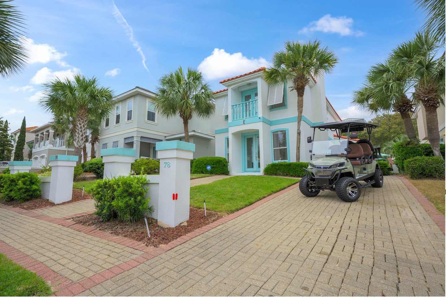 A charming brick home with a golf cart parked in the driveway, surrounded by lush green grass and landscaping.