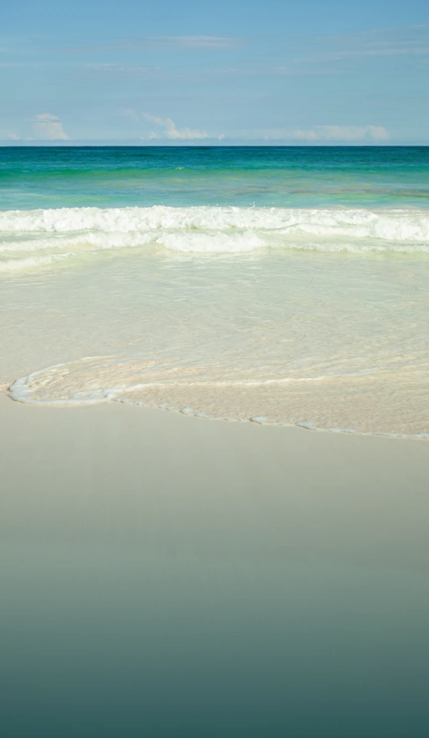 Calm beach with gentle waves and sand.