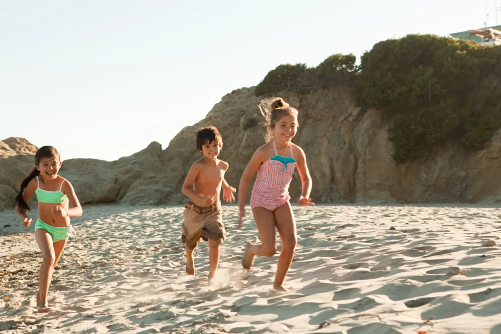 Three children running on a sandy beach