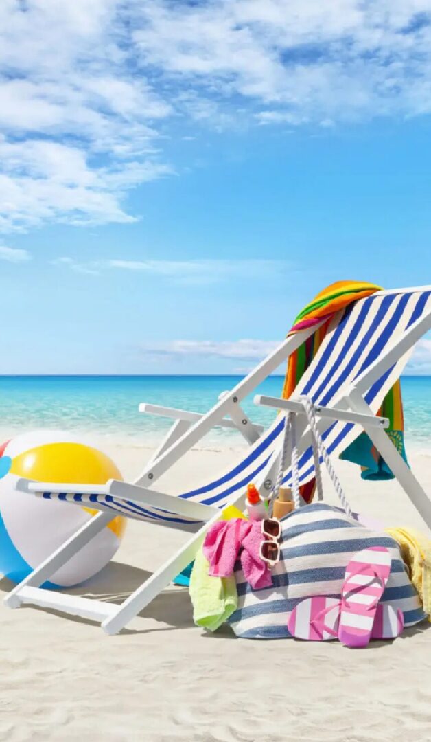 Colorful beach scene featuring a striped lounge chair, towels, a beach ball, and flip-flops on sandy shores.